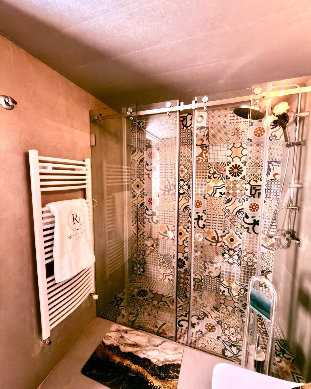 A bathroom with a shower, a towel rack with a towel, and a patterned shower curtain.