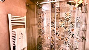 Une salle de bain avec une douche, un porte-serviettes avec une serviette, et un rideau de douche à motifs.