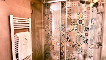 A bathroom with a shower, a towel rack with a towel, and a patterned shower curtain.