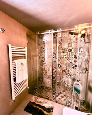 A bathroom with a shower, a towel rack with a towel, and a patterned shower curtain. - Casa Di Romeo E Juliet (Faraya)