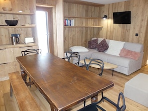A wooden interior with a dining table, chairs, a sofa, and a television. - Modern apartment with terrace - 6 guests (Pralognan-la-Vanoise)
