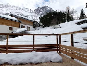 A wooden deck with snow accumulation, overlooking a mountainous landscape with buildings. - Modern apartment with terrace - 6 guests (Pralognan-la-Vanoise)