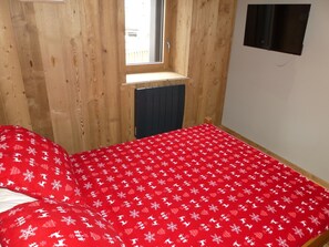 A room with a bed, a window, and a radiator. - Modern apartment with terrace - 6 guests (Pralognan-la-Vanoise)