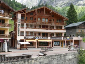 A multi-story wooden building with balconies, ski rental, and surf shops. - Ideal apartment with balcony - 4 guests (Pralognan-la-Vanoise)