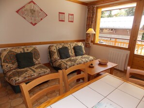 Ein gemütliches Zimmer mit zwei gestreiften Sofas, einem Holztisch und einem Fenster mit Blick.