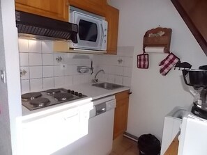 A compact kitchen with white cabinets, a microwave, a stove, a sink, and a dishwasher. - Apartment with stunning view - 6 guests (Pralognan-la-Vanoise)