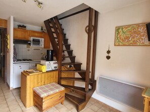 A compact kitchen with a microwave, toaster, and coffee maker on a wooden counter. A wooden bench with a plaid cushion is placed in front of a wooden staircase. - Apartment with stunning view - 6 guests (Pralognan-la-Vanoise)