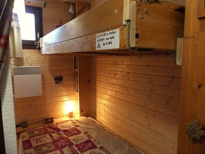 A compact room with a bunk bed, a heater, a quilted bedspread, and a sign indicating a 6-year-old's room. - Renovated studio, mountain view - 4 guests (Pralognan-la-Vanoise)