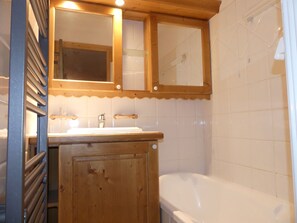A bathroom with a wooden vanity, a sink, a mirror, and a bathtub. - Cozy and sunny apartment - 4 guests (Pralognan-la-Vanoise)