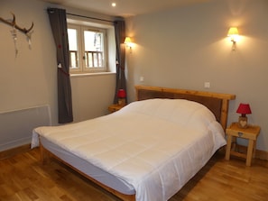 A bedroom with a wooden bed, two bedside lamps, a window with curtains, and a wall-mounted star decoration. - Charming apartment - 7 guests (Pralognan-la-Vanoise)