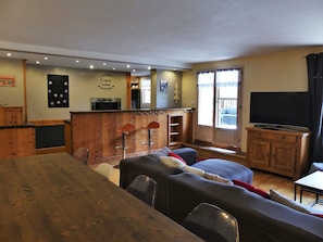 A cozy living room with a wooden dining table, a sofa, and a TV. - Charming apartment - 7 guests (Pralognan-la-Vanoise)