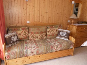 A wooden sofa with patterned cushions and a wooden dresser with a lamp. - Studio-cabin with stunning view - 4 guests (Pralognan-la-Vanoise)