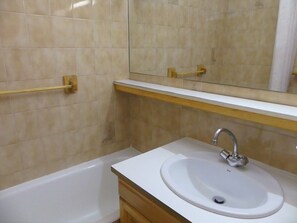 A bathroom with a white sink, a mirror above it, and a bathtub. - Studio-cabin with stunning view - 4 guests (Pralognan-la-Vanoise)