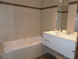 A modern bathroom with a bathtub, a vanity with a mirror, and tiled walls. - Spacious apartment with balcony - 8 guests (Pralognan-la-Vanoise)