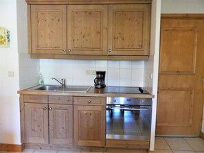 Eine Küche mit Holzausstattung, einer Edelstahl-Spüle, einer Kaffeemaschine und einem Backofen.