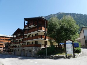 Ein mehrstöckiges Hotel mit Balkonen, einer Stein-Fassade und einem Schild, das auf einen Skiort hinweist.