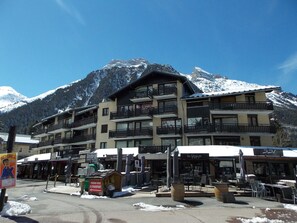 Ein mehrstöckiges Hotel mit Balkonen, einem Parkplatz und Sitzgelegenheiten im Freien.