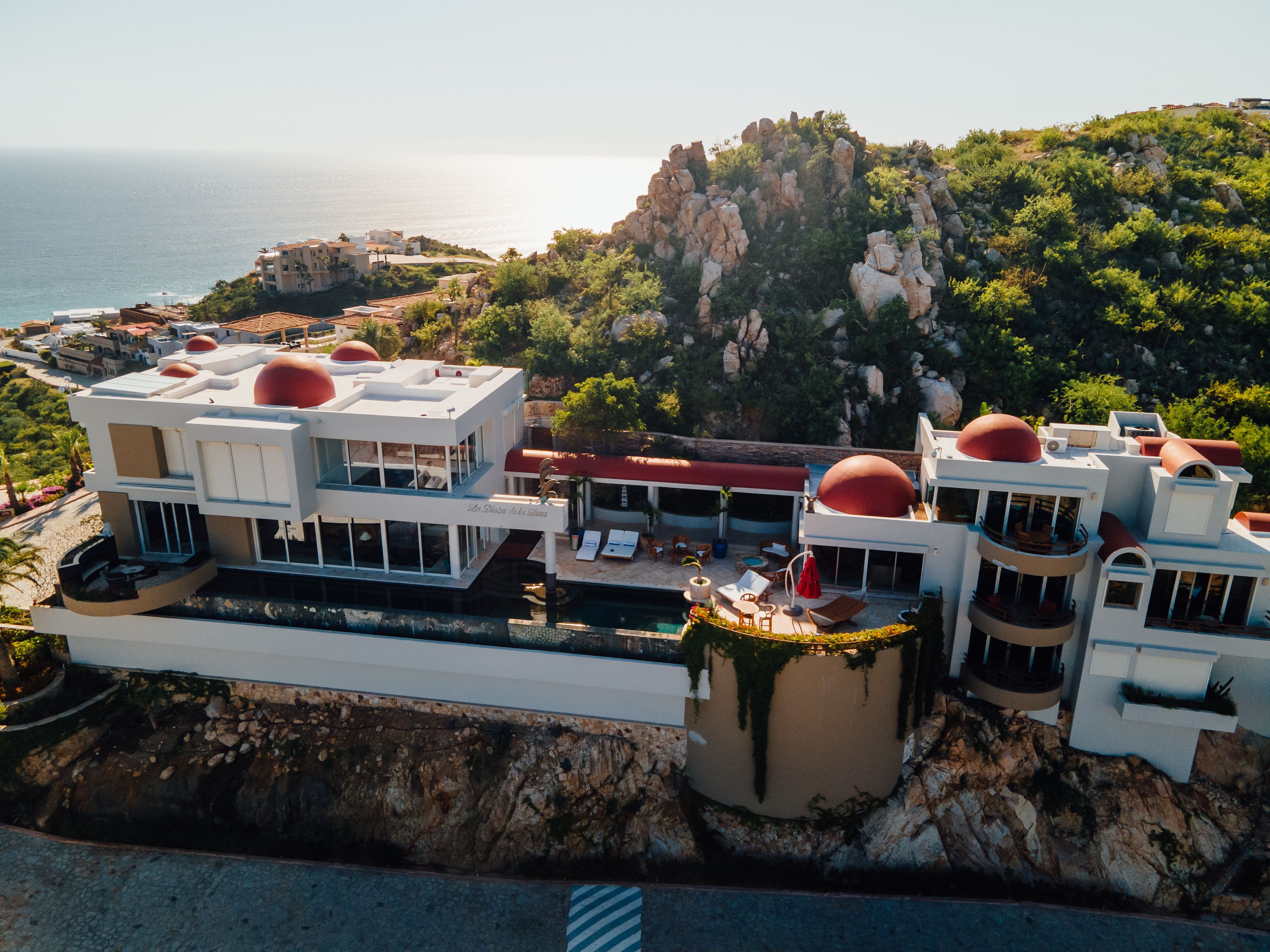 A coastal hotel with multiple buildings, a pool area, and a view of the sea.