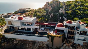 A coastal hotel with multiple buildings, a pool area, and a view of the sea.