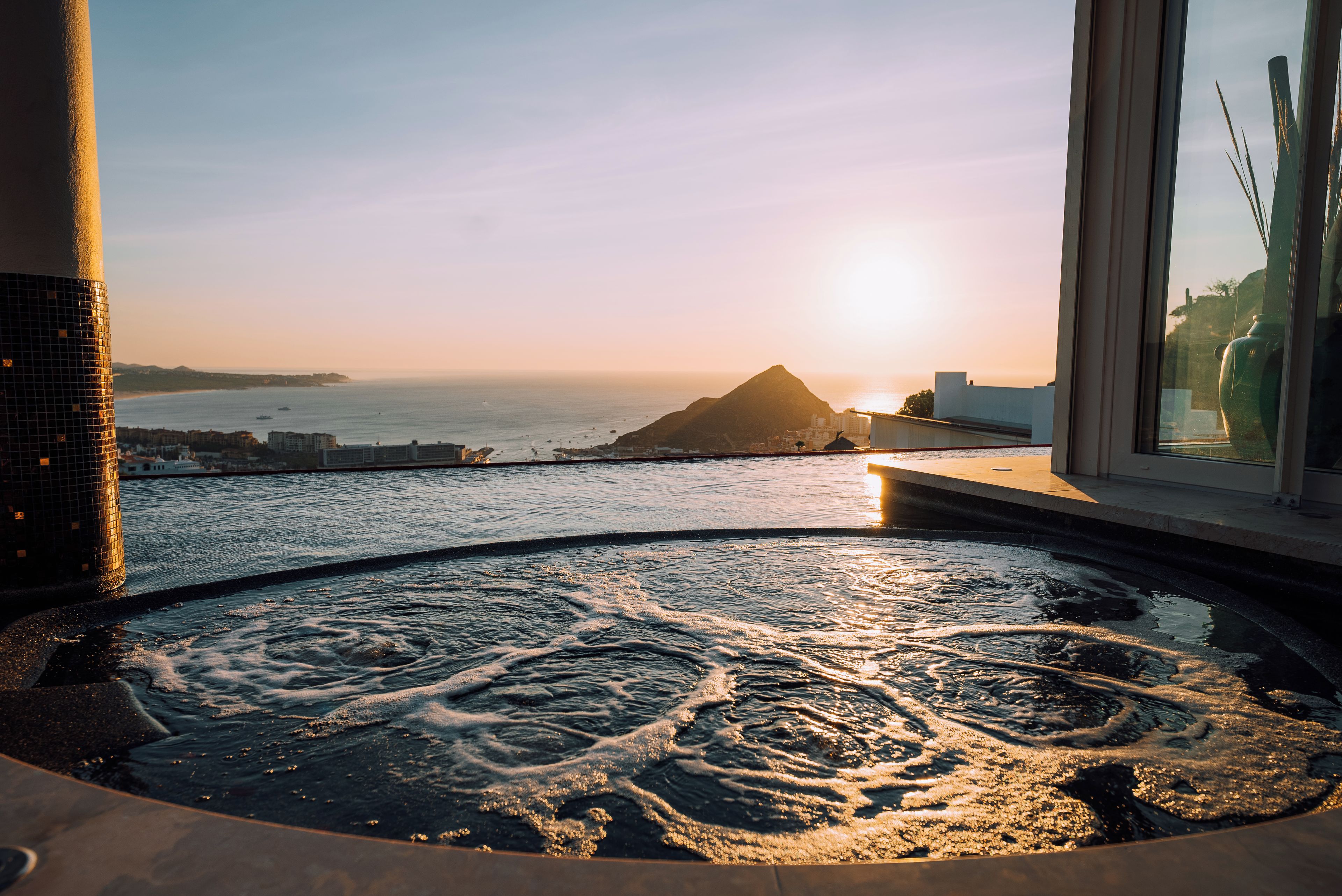 A hot tub with a view of the ocean and a mountain in the distance.