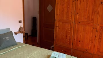 Un dormitorio con cama, un armario de madera y una puerta que da a otra habitación.