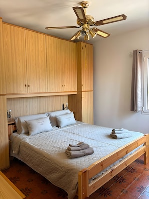 Ein Schlafzimmer mit einem hölzernen Bett, einem Deckenventilator und einem Fenster mit Vorhängen.