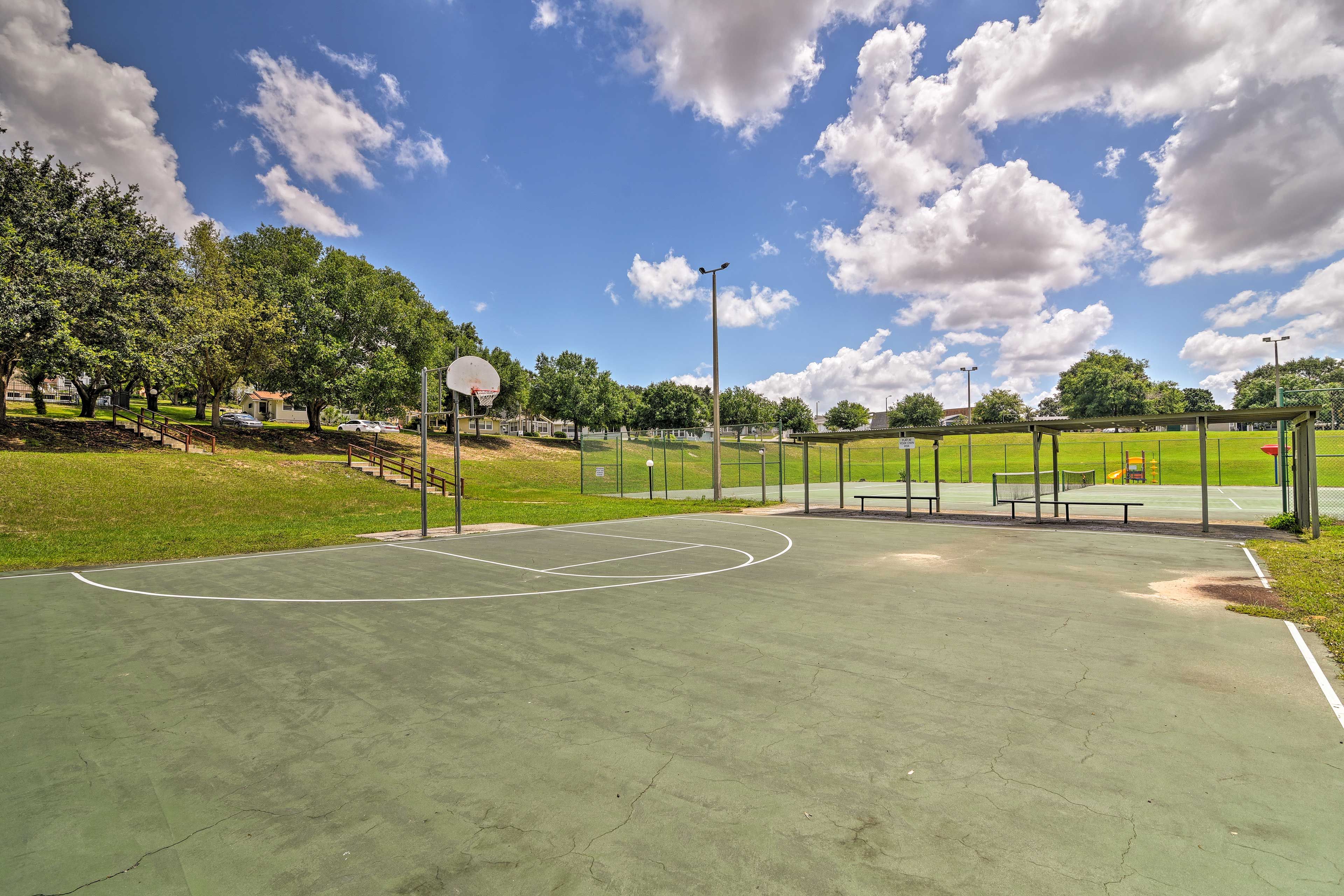A basketball court with a hoop, benches, and a fence.