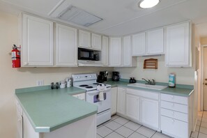 A kitchen with white cabinets, a microwave, a stove, a sink, and a coffee maker. - 'tropical Hideaway' 3 Mi to Lake Louisa State Park (Clermont)