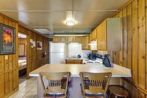 A kitchen with wooden cabinets, a refrigerator, a microwave, and two wooden chairs. - Happy Hour Hideaway: Pool, Dock & Lake Access (Clermont)