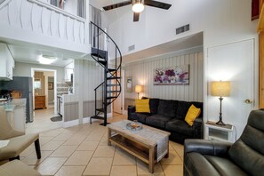 A spacious living area with a staircase, a sofa, a coffee table, and a dining area. - Lake Breeze Bungalow: 3 Mi to State Park! (Clermont)