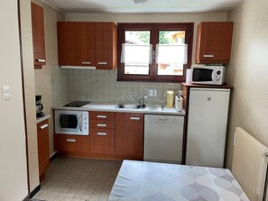 Cozinha compacta com armários de madeira, micro-ondas, torradeira, cafeteira e lava-louças.
