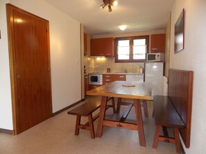 A compact kitchen with wooden cabinets, a microwave, a refrigerator, and a dining table with benches. - Spacious apartment for families - 6 guests (Pralognan-la-Vanoise)