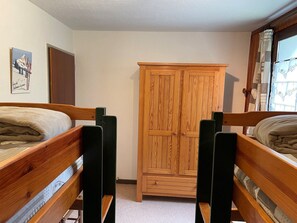 A bedroom with two wooden bunk beds, a wooden wardrobe, and a window with curtains. - Spacious apartment for families - 6 guests (Pralognan-la-Vanoise)