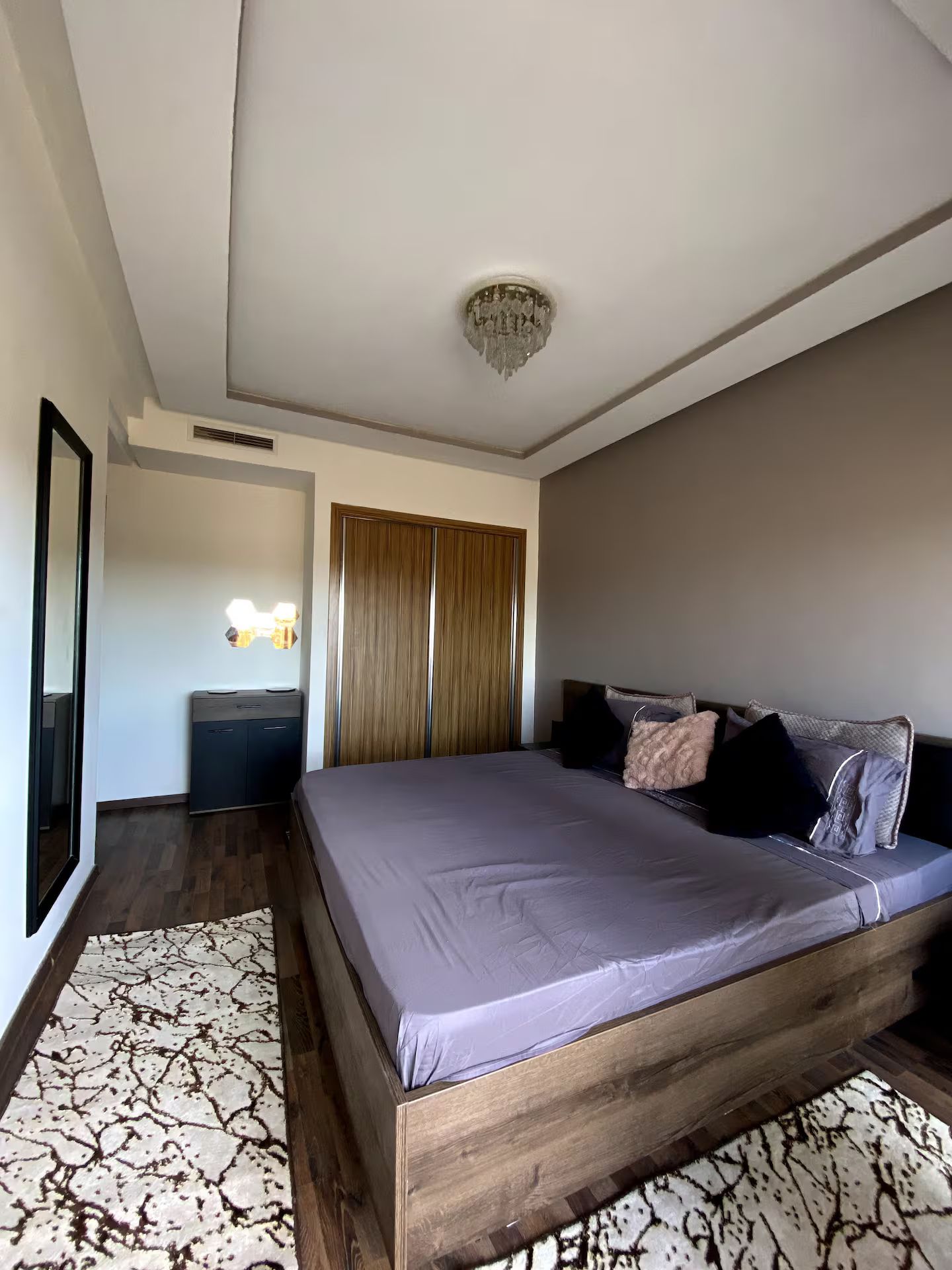 Ein Schlafzimmer mit einem großen Bett, einem Kleiderschrank, einem Schreibtisch und einem Spiegel.