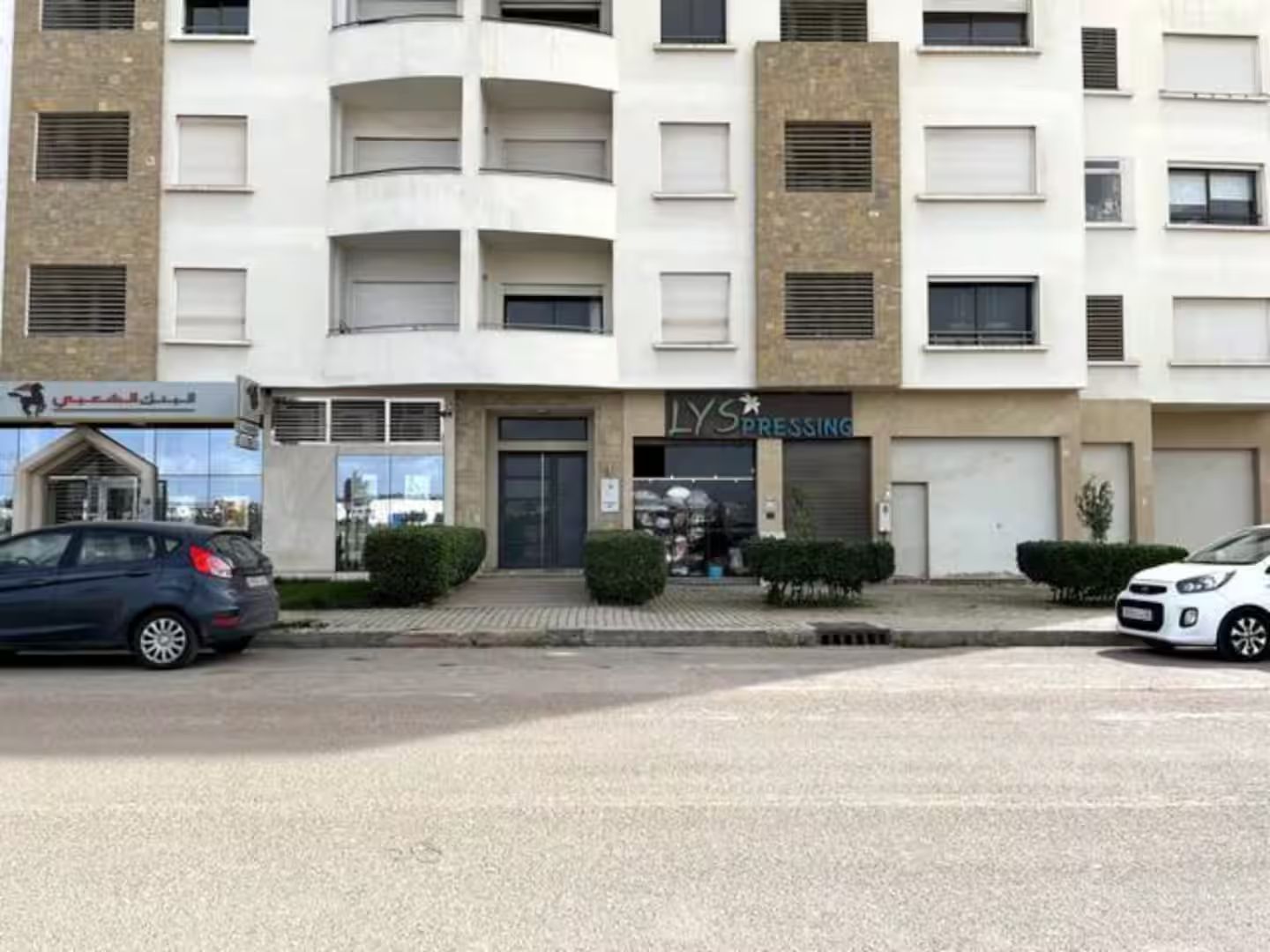 Ein mehrstöckiges Gebäude mit Geschäftsflächen im Erdgeschoss, darunter ein Ladengeschäft mit Beschilderung.