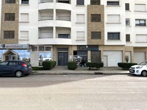 Un edificio de varios pisos con locales comerciales en la planta baja, incluyendo un escaparate con señalización.