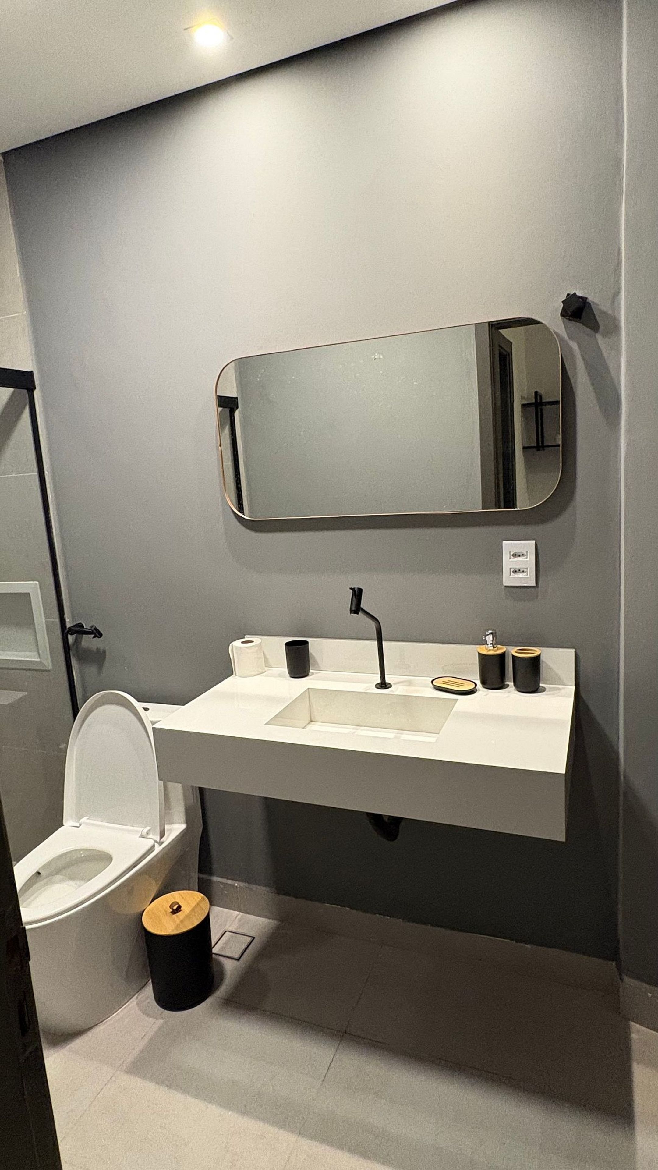 A modern bathroom with a white sink, black faucet, and a mirror above it.