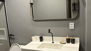 Casa de banho moderna com lavatório branco, torneira preta e espelho em cima.