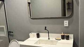 A modern bathroom with a white sink, black faucet, and a mirror above it.
