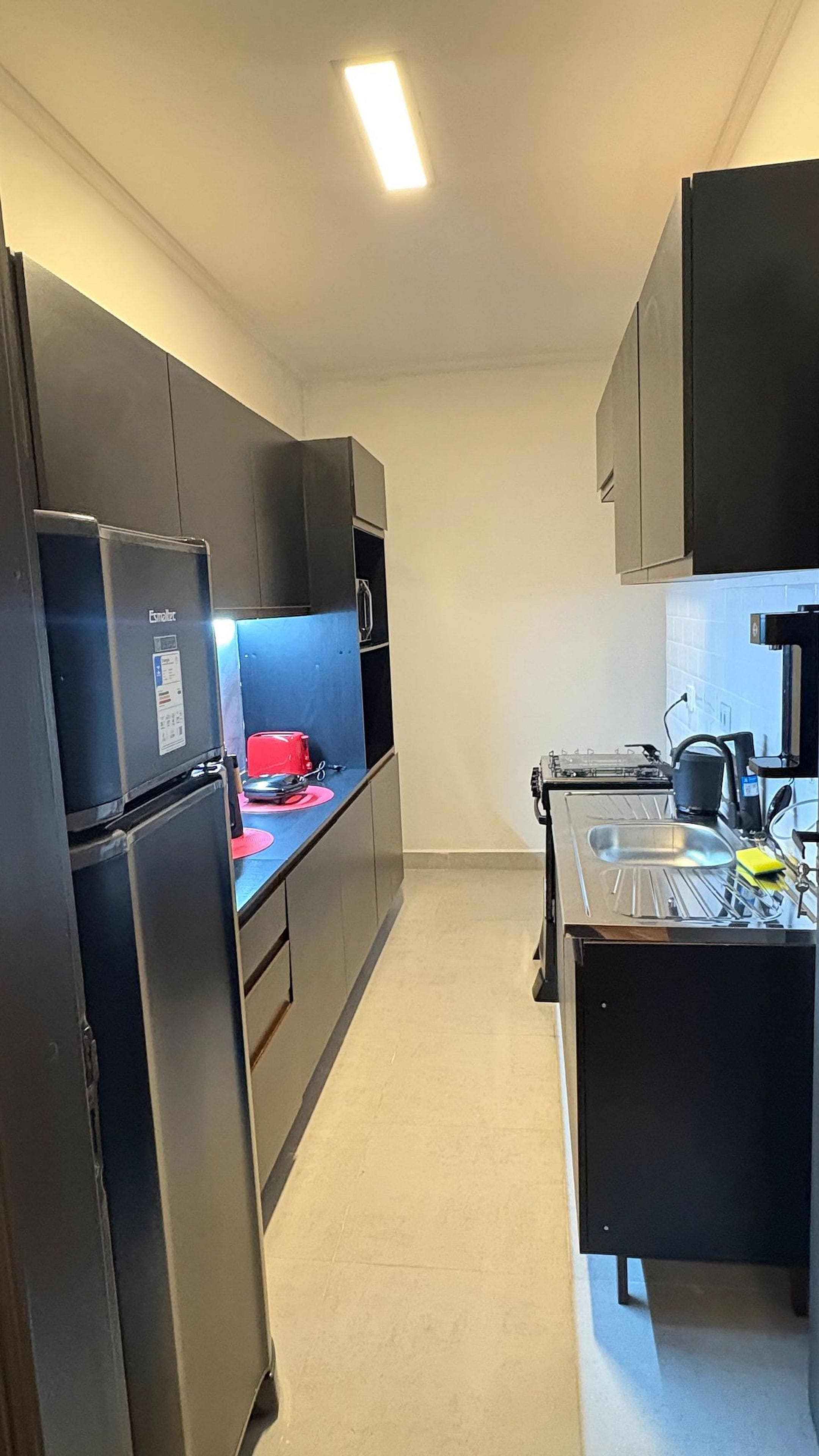 A compact kitchen with a refrigerator, stove, and sink.