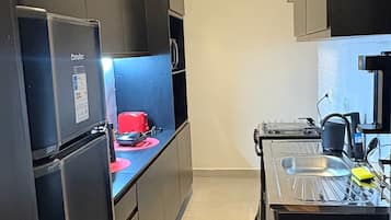 A compact kitchen with a refrigerator, stove, and sink.