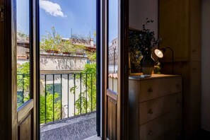 Ein Zimmer mit Blick auf einen Balkon, einem Schminktisch mit Lampe und einer Topfpflanze.