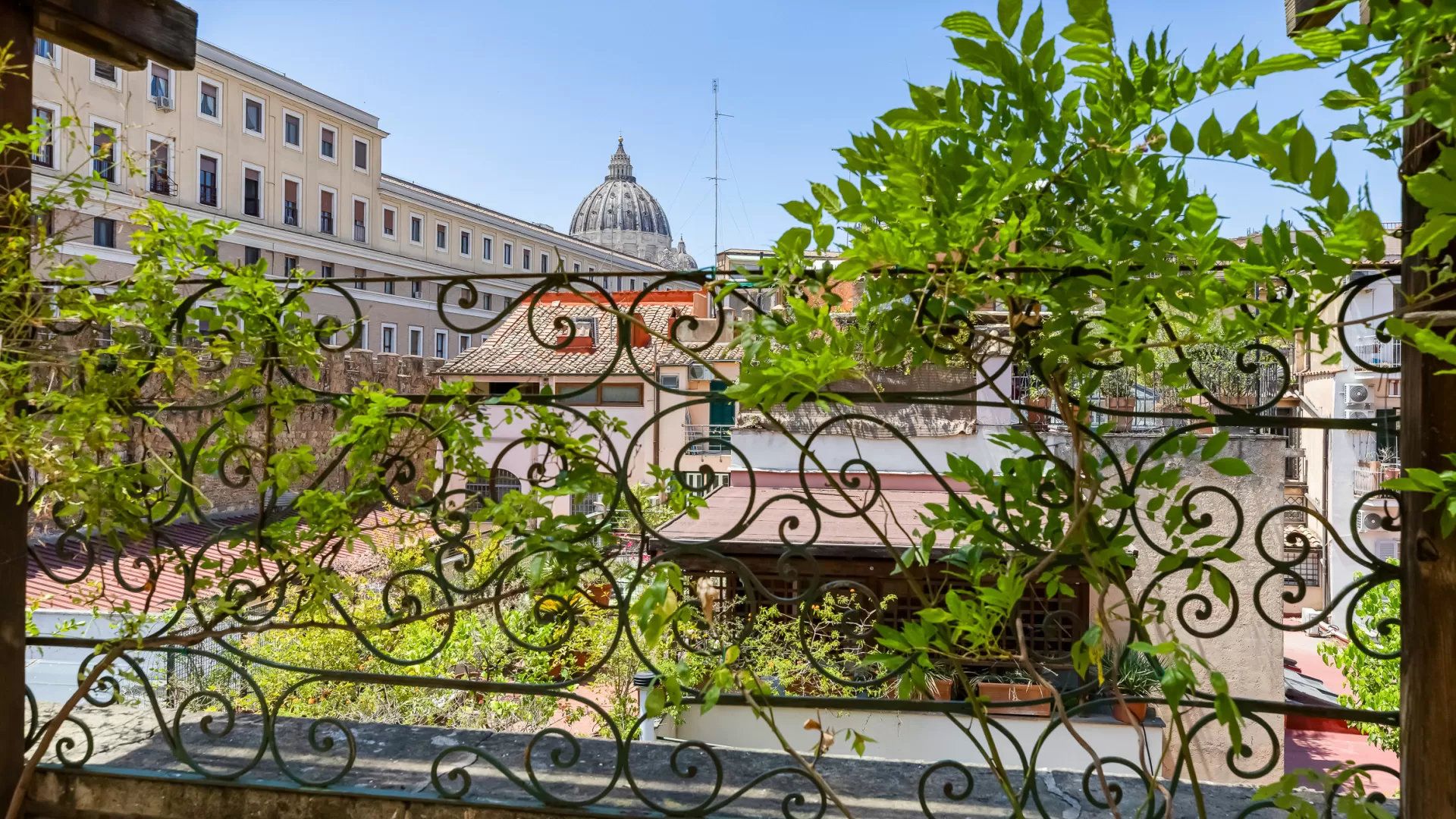 A view through a wrought iron fence with buildings in the background, including a prominent dome structure.