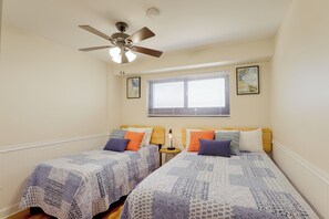 A bedroom with two beds, a ceiling fan, a window with blinds, and two wall-mounted paintings. - Ocean-view Balcony! Myrtle Beach Resort Getaway (Myrtle Beach)