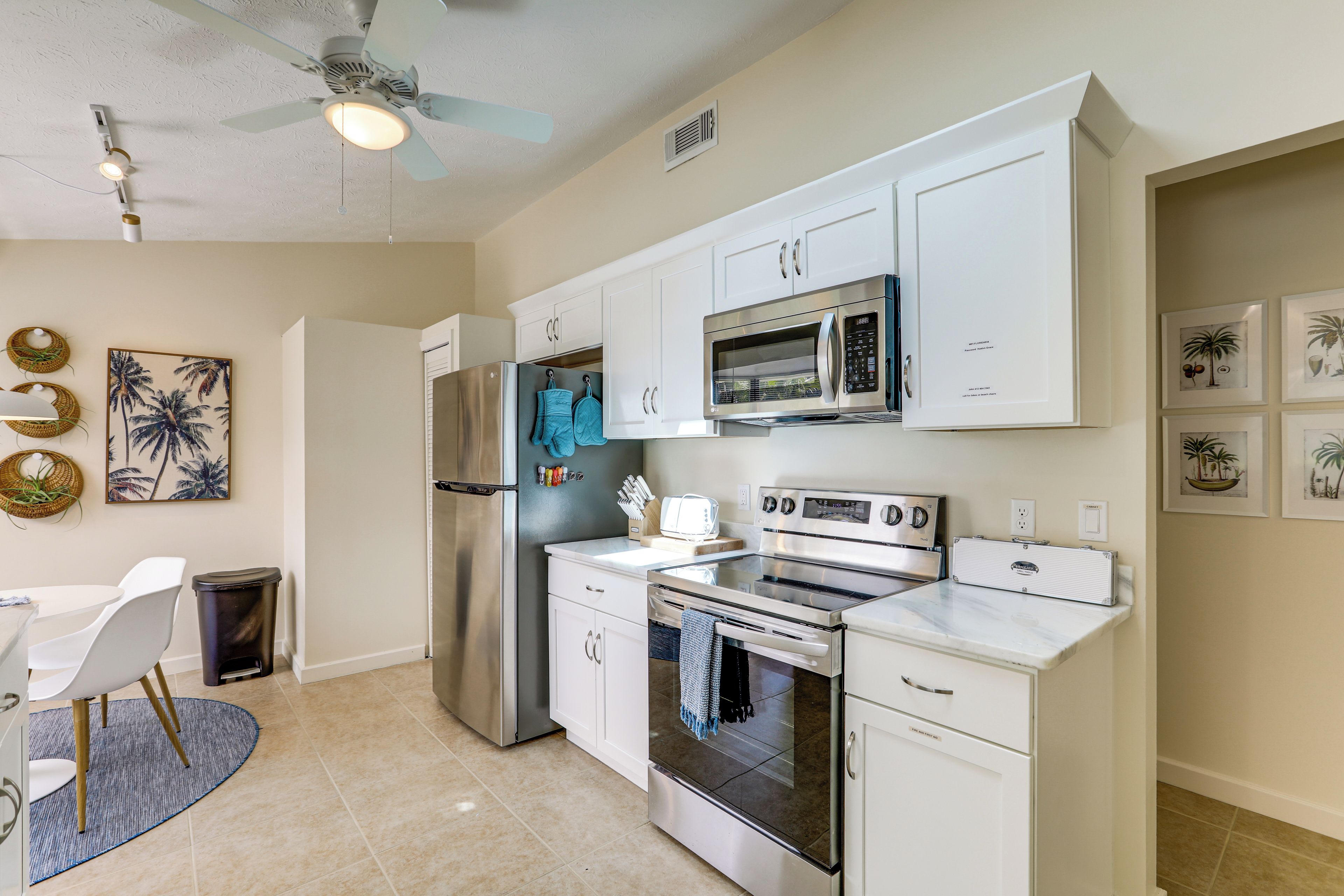 A modern kitchen with white cabinetry, stainless steel appliances, and a dining area with a white table and chairs.