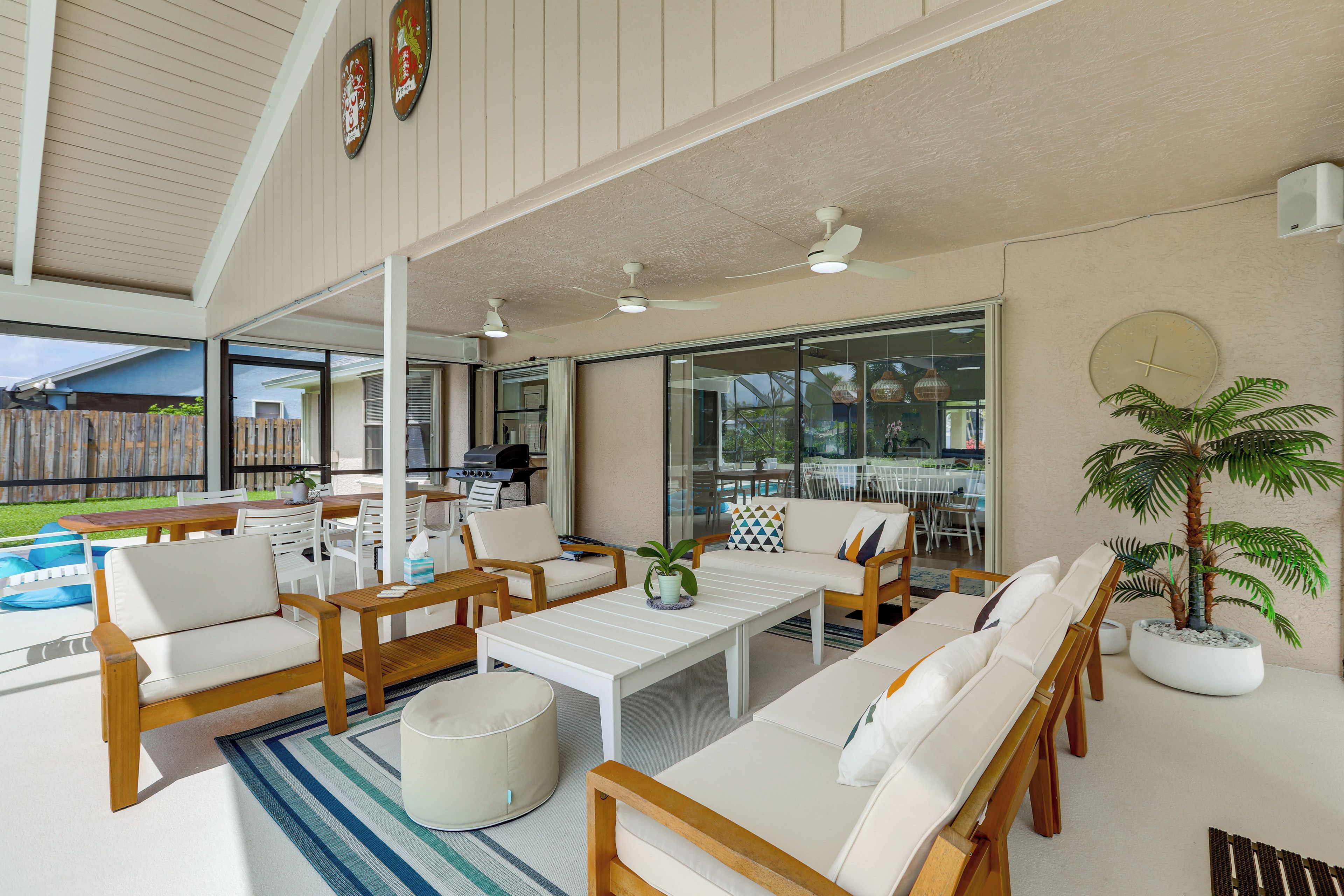 Un espacio de estar abierto con vista a la piscina, mobiliario exterior y ventiladores de techo.