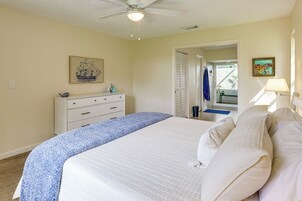 Un dormitorio con cama, cómoda, ventilador de techo y puerta que da a un balcón.
