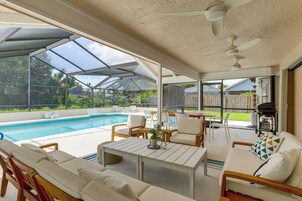 Un espacio al aire libre techado con piscina, asientos y una mesa.