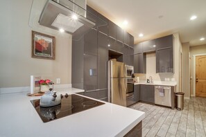 Eine moderne Küche mit Edelstahlkühlschrank, Backofen und einer großen Kochinsel mit Wasserkocher.