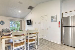 A kitchen with a dining table, chairs, a refrigerator, and a television mounted on the wall. - Family-friendly St. Augustine Home w/ Game Room (St. Augustine)
